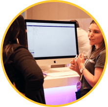 Employee engages with MOMENTUM attendee in front of computer displaying ModMed software