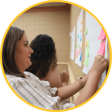 MOMENTUM attendees place post-it notes on a white board during DesignLab session